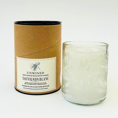 Candle in a glass container with a cardboard tube labeled 'Unwined Sauvignon Blanc' on a white background
