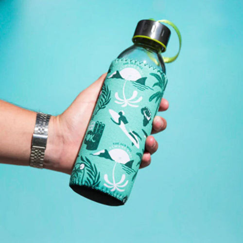 Hand holding a teal water bottle with a pattern against a blue background