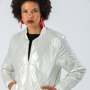 Woman wearing a Signature by Des shiny white puffer jacket with red earrings 