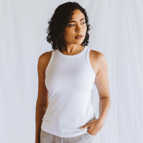 Woman wearing a white tank top against a plain background