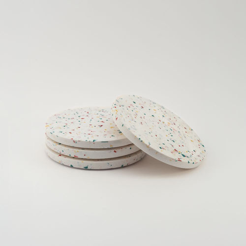 Set of four round speckled coasters on a light gray background