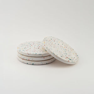 Set of four round speckled coasters on a light gray background