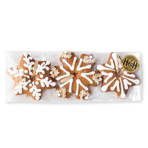 Packaged star-shaped gingerbread cookies with white icing and gold accents on a white background